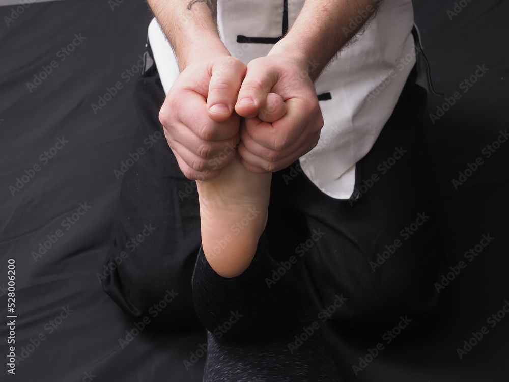 male massage therapist doing a foot massage to a woman