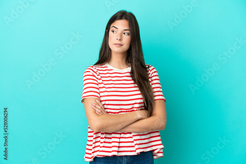 Young Brazilian woman isolated on blue background looking to the side © luismolinero