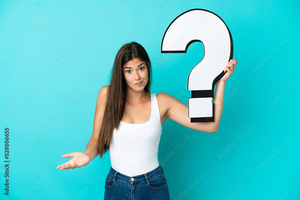 Young Brazilian woman isolated on blue background holding a question mark icon and having doubts Young Brazilian woman isolated on blue background holding a question mark icon and having doubts