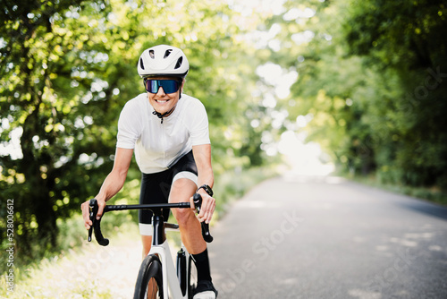 Rennradfahrer, sportliche Frau in Fahrradkleidung und mit Helm beim Sport Fototapet
