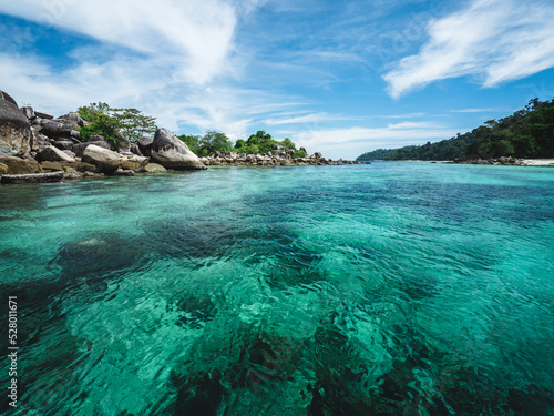 Scenic view of Koh Phueng Island crystal clear emerald sea water with coral reef against summer blue sky. Snorkeling spot near Koh Lipe Island  Tarutao National Marine Park  Satun  Thailand.