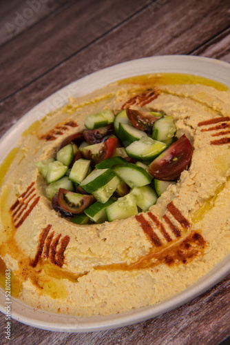 Homemade hummus with tahini plate with olive oil, parsley and paprika isolated on brown background. High quality photo