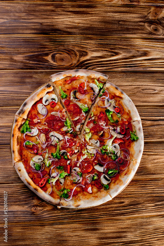 Vegan pizza with tomato sauce, cherry tomatoes, mushrooms, broccoli, red onion on woden background. View from above