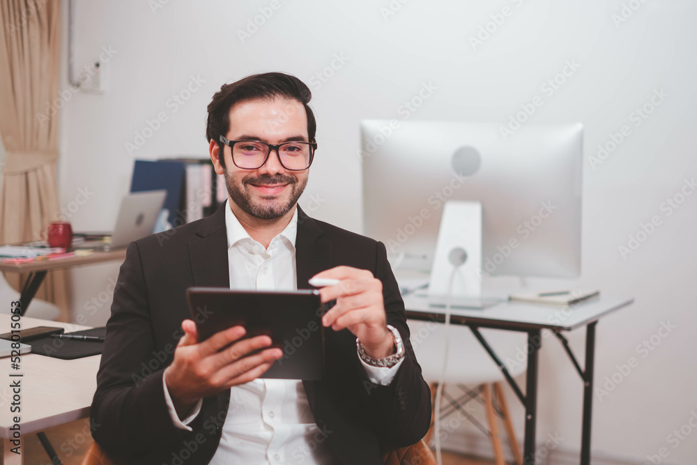 Businessman, Confident Male executive commuter is looking at hand held digital tablet screen. Confident professional making successful plan while working on laptop at office. Businessman, Confident Male executive commuter is looking at hand held digital tablet screen. Confident professional making successful plan while working on laptop at office.
