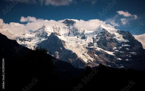 A great view of a snowy mountain massif and Jungfrau peak under a dramatic sky. Switzerland, Europe.