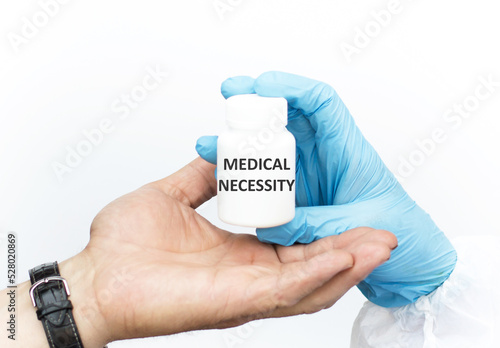 Medical necessity text on a white jar of medicine, the doctor passes it to the patient's hand