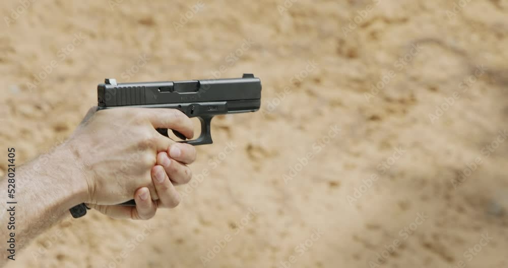 Slow motion of a hand gun firing in a firing range with cartridge flying away Slow motion of a hand gun firing in a firing range with cartridge flying away