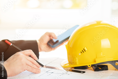architect builder foreman in the office at the construction site with blueprints projects of buildings works with a phone and a ruler,industrial meeting