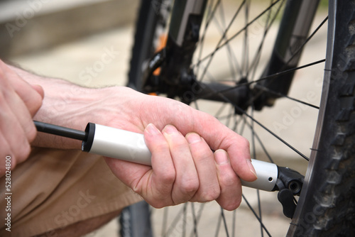 Men's hands Inflate a bicycle wheel with a bicycle pump Outdoors
