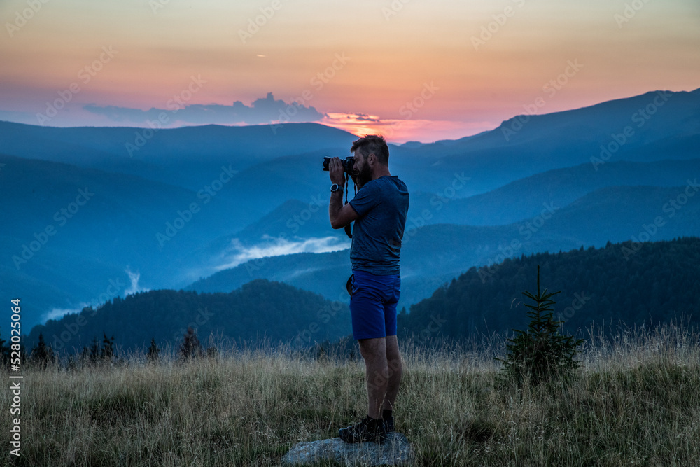 man taking photos of sunset in mountains