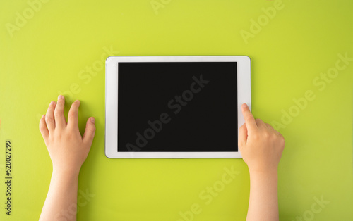 High angle shot of a little kid using a digital tablet with tablet computer on green background in horizontal with copy space.