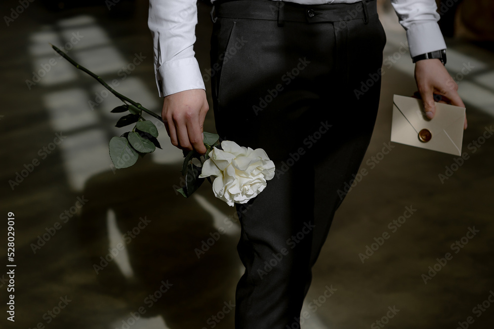 Young groom at the training ceremony holding a white rose and a letter from the bride Young groom at the training ceremony holding a white rose and a letter from the bride