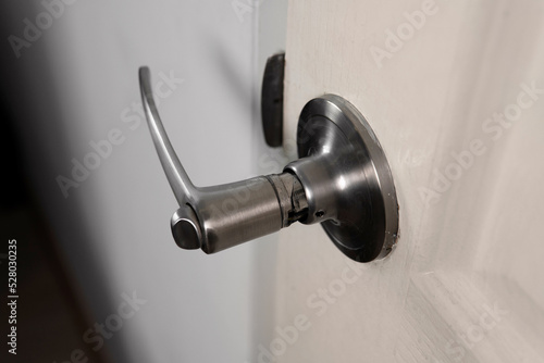 Entrance bedroom door with closeup broken silver color stainless steel door handle against interior white wall at home background