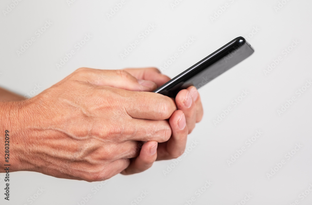 Man hands closeup texting message at phone. Male using messenger or searching information on Internet.