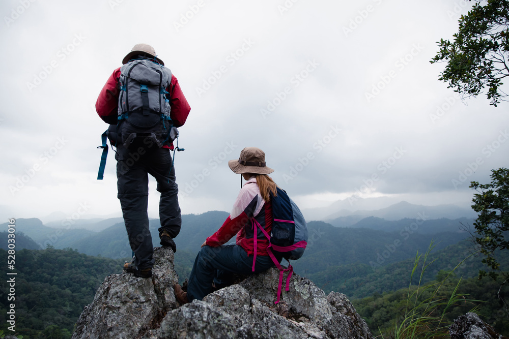 Young tourist couple watching spectacular mountain scenery in high mountains. man and woman hiker on top rock. A couple of travelers in love. People greet the dawn. Lovers travel. Copy space