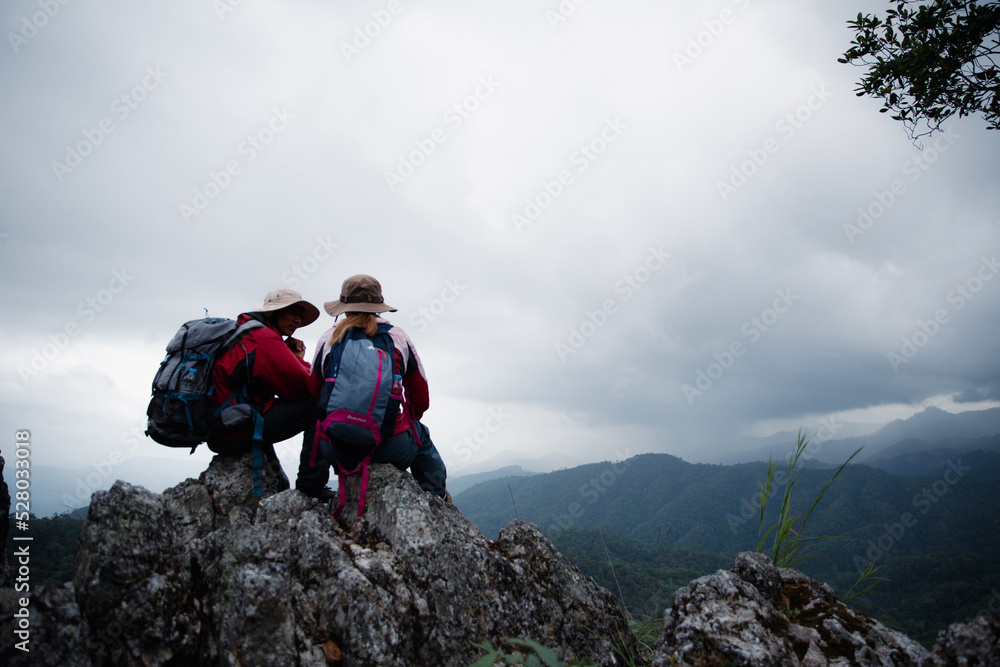 Young tourist couple watching spectacular mountain scenery in high mountains. man and woman hiker on top rock. A couple of travelers in love. People greet the dawn. Lovers travel. Copy space