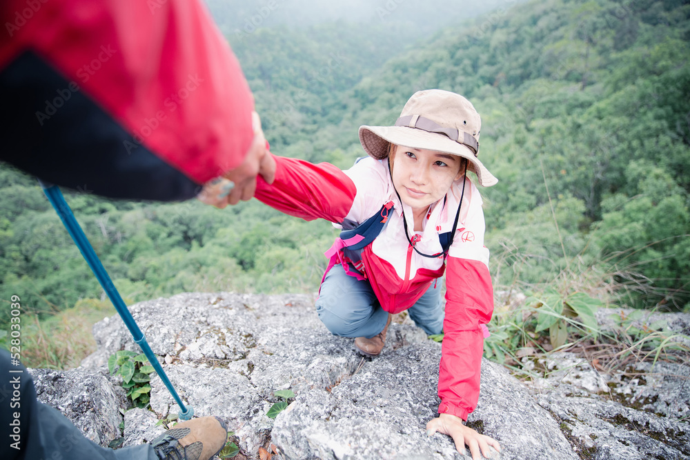 Person hike friends helping each other up a mountain. Man and woman giving a helping hand and active fit lifestyle. Asia couple hiking help each other. concept of friendship, teamwork. Person hike friends helping each other up a mountain. Man and woman giving a helping hand and active fit lifestyle. Asia couple hiking help each other. concept of friendship, teamwork.