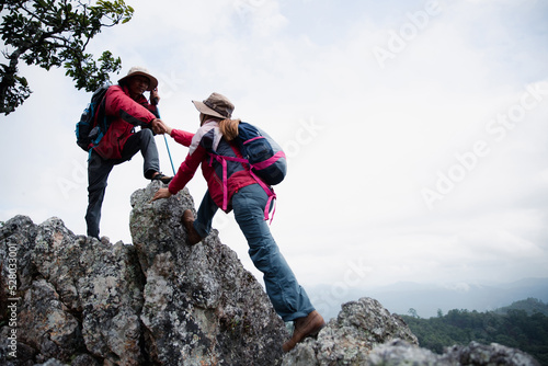 Person hike friends helping each other up a mountain. Man and woman giving a helping hand and active fit lifestyle. Asia couple hiking help each other. concept of friendship, teamwork.
