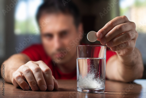 Photography A man takes a cure for a hangover at home, throws a second fizzy pill into a gla
