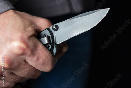 Fotografi Man holding a knife in a threatening stance ready to fight