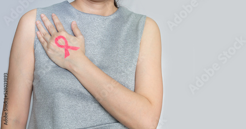 Asian woman are show Pink ribbon which draw by lip stick on back hand and touch breast to encourage breast cancer patient. Breast cancer campaign in October month