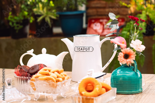 Mesa de café da manha com chá, flores e doces photo