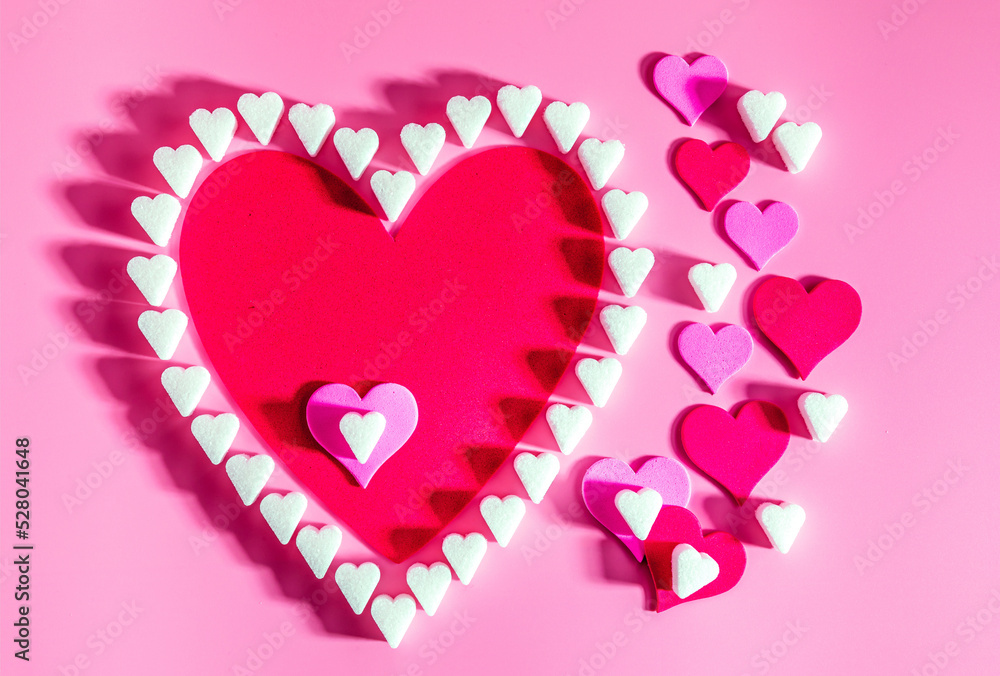 Sugar hearts and other hearts on a pink background with copy space, concept of love and romance