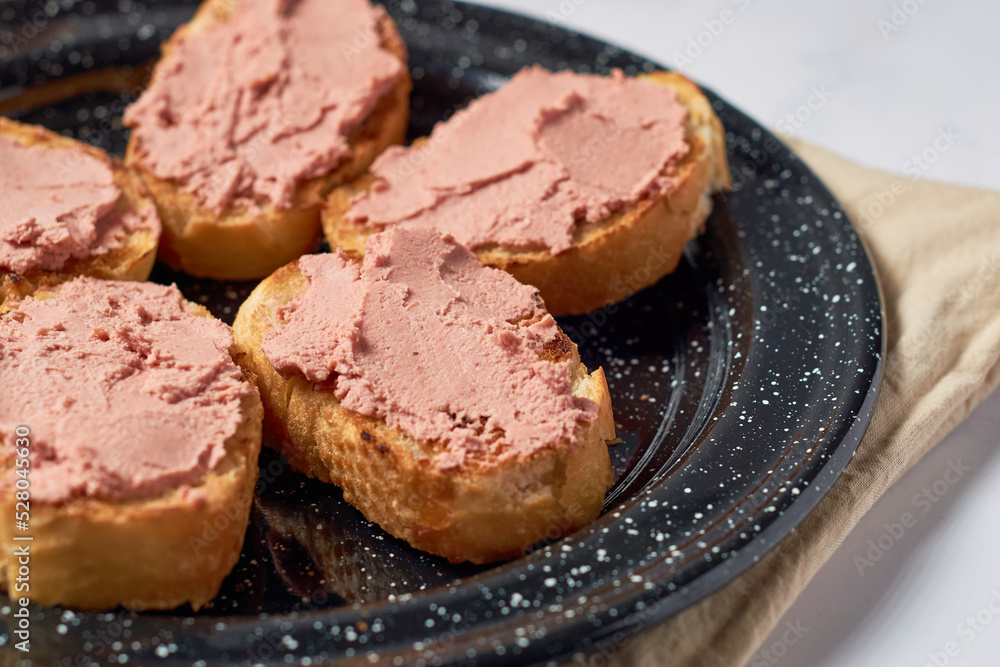 Homemade beef liver pate in a glass jar and baguette slices with pate