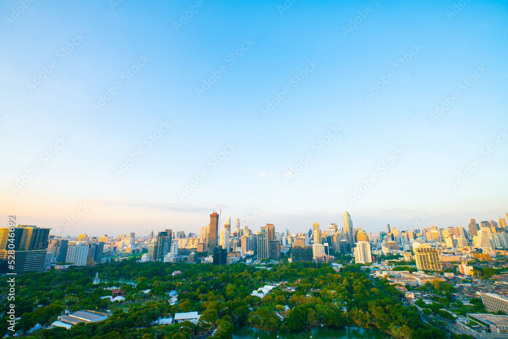 Fototapeta premium Modern office building and hotel with tree park in city of Bangkok against blue sky cloud
