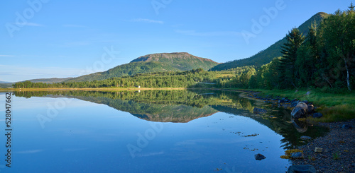 Mountain range in the Lofoten Island  Norway with a symmetry reflection in the water of a lake. Natural mirror. Sunny morning without clouds in the sky. Summer vacation in Lofoten.