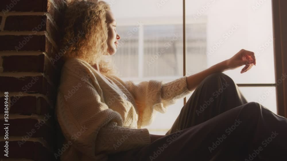 Young blond curly caucasian woman sitting on the loft window Young blond curly caucasian woman sitting on the loft window