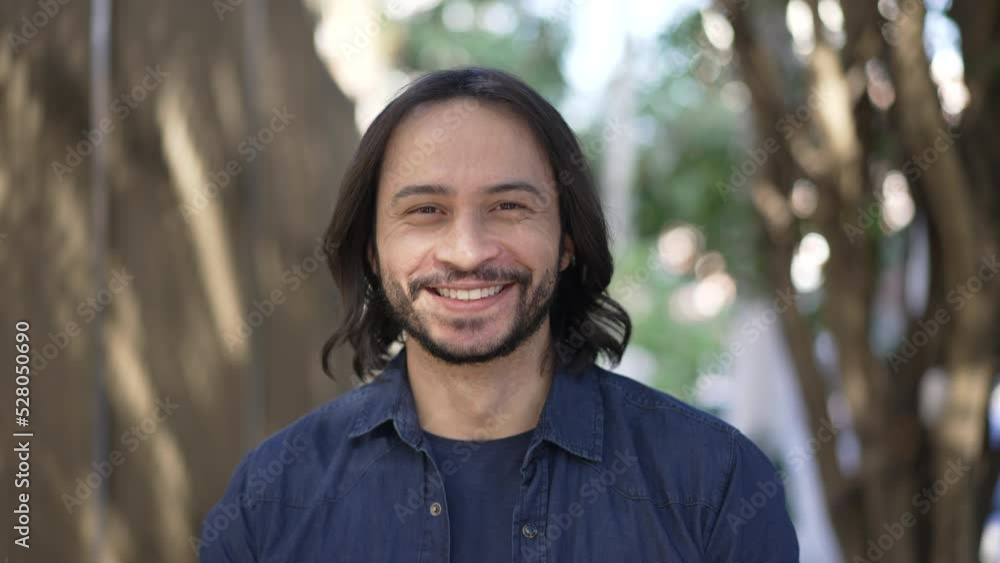 Portrait of a happy hispanic young man walking forward in city street. Casual South American Brazilian person face closeup Portrait of a happy hispanic young man walking forward in city street. Casual South American Brazilian person face closeup