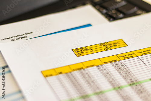 Fotografija Close up shot of a print outs of excel table of a bank loan amortization table, personal balance sheet and laptop