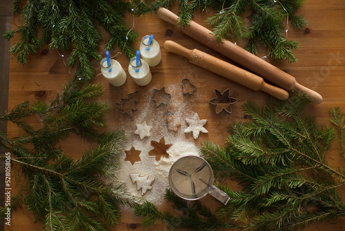 Ginger cookies and scattered flour on the table, with coniferous branches