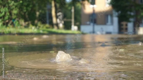 A pipe burst causes street flooding on a sunny day