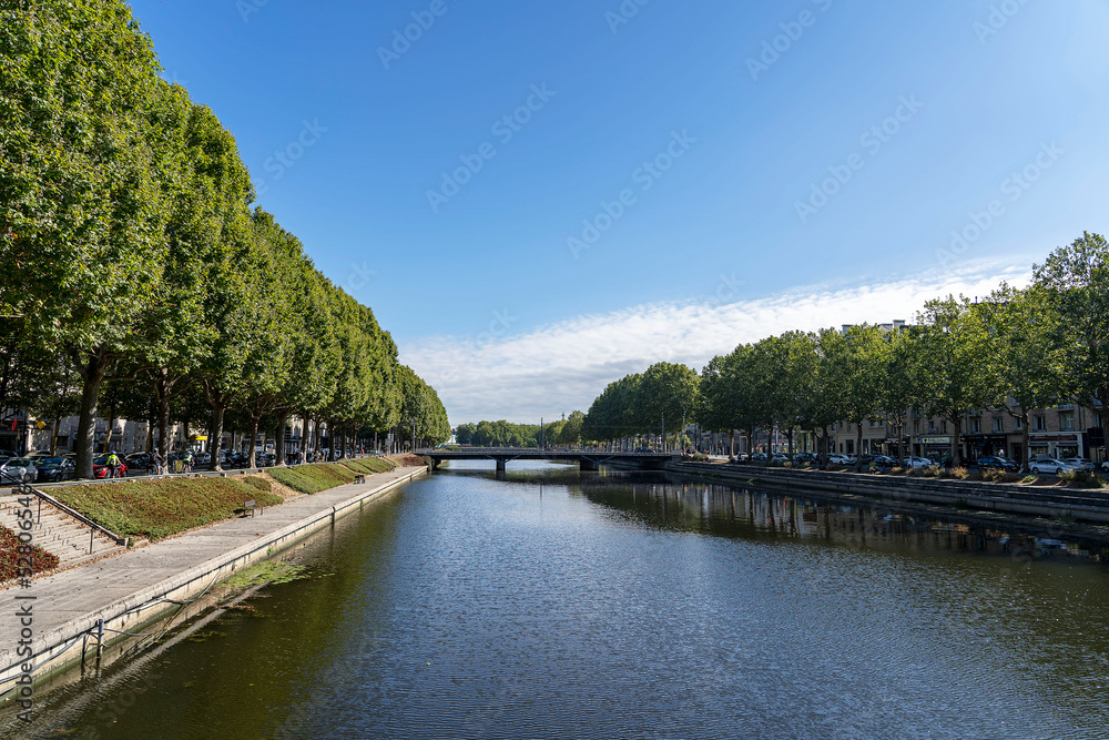 Caen, France - 24 July 2022: River Orne and its two banks with numerous plane trees with lush green crowns in sunny weather, Normandy.