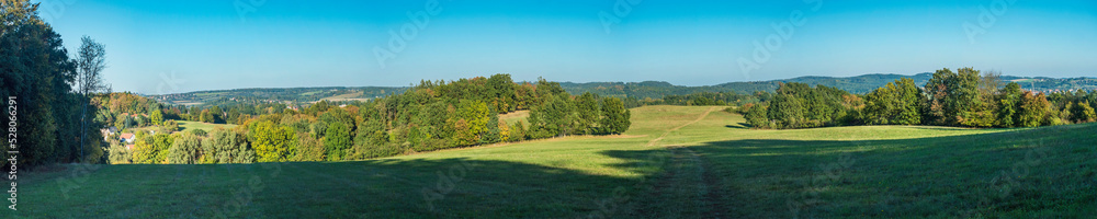 Ultra wide panoramic late summer landscape with idyllic green meadow, trees, forest and hills with clear blue sky, Czech republic, central bohemia