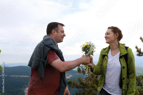 Husband gives his wife bouquet of wildflowers on Lago-Naki Plateau
