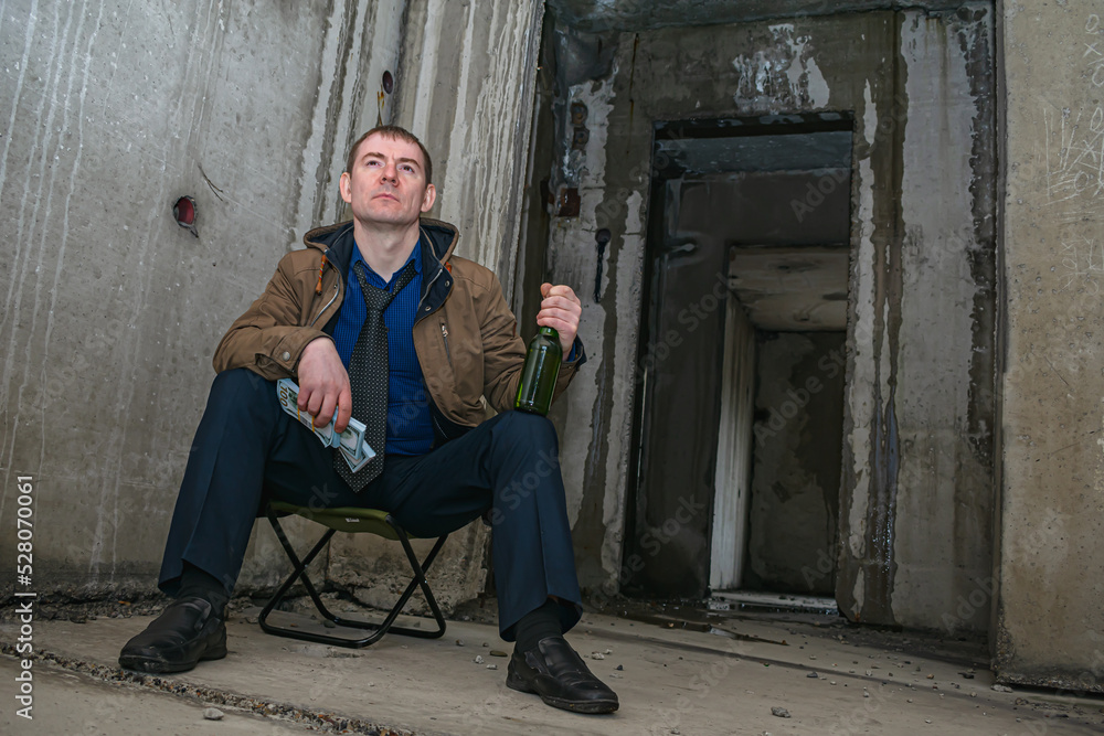 Ruined businessman in desperation gets drunk with alcohol in a ruined building Ruined businessman in desperation gets drunk with alcohol in a ruined building