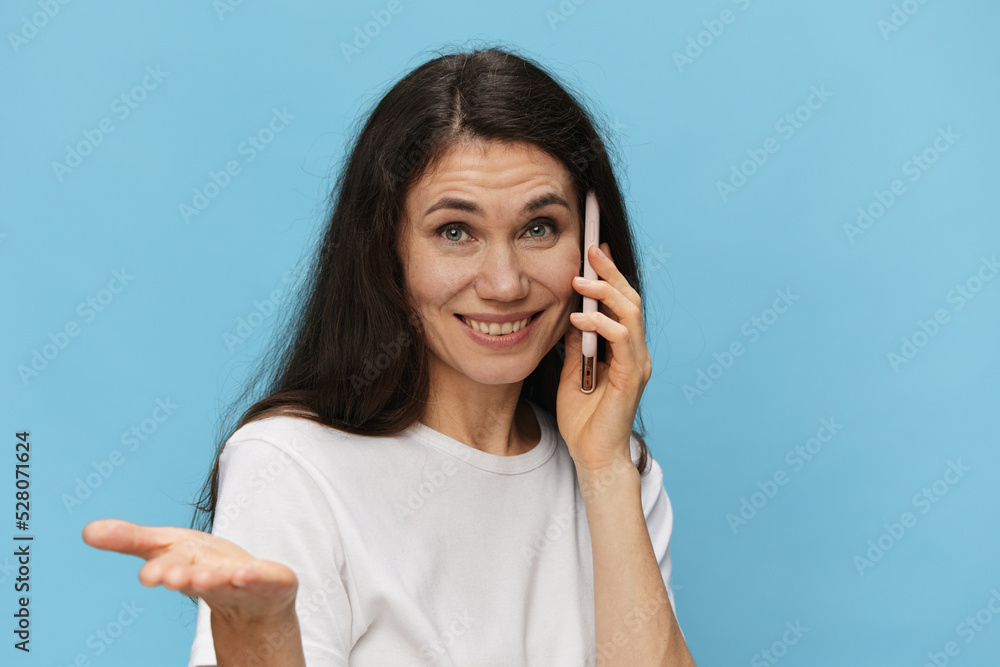 cute, beautiful woman talking on the phone smiling broadly and extending her hand to the camera, standing on a light blue background with empty space to insert an advertising mockup cute, beautiful woman talking on the phone smiling broadly and extending her hand to the camera, standing on a light blue background with empty space to insert an advertising mockup