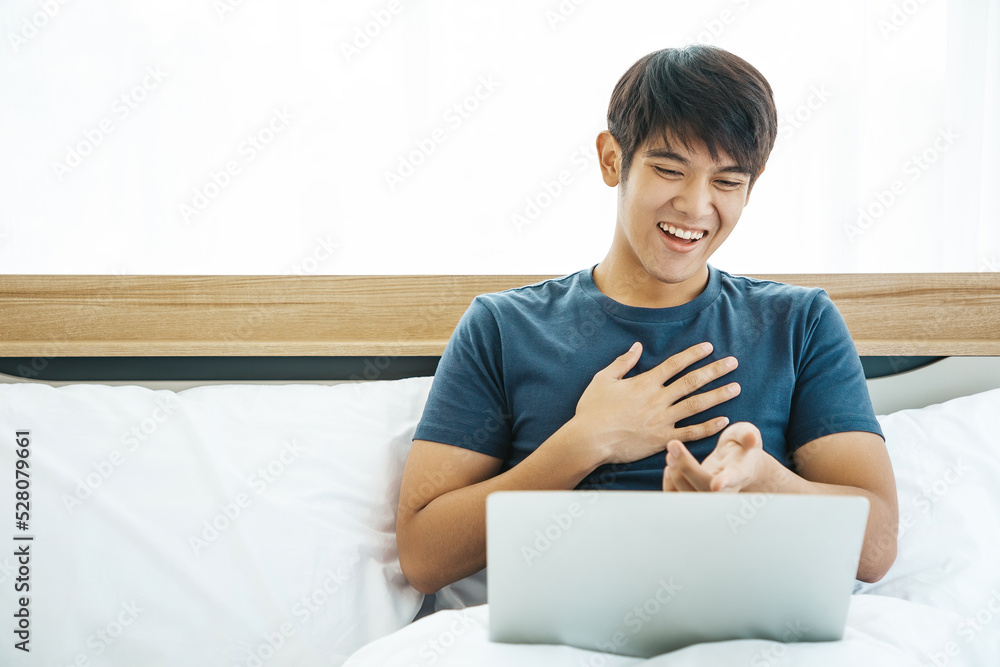 Happy man using Laptop computer and checking good News in the Bedroom. COPY SPACE. Trading. Watching Movie. WORK FROM HOME WFH Concept. Happy man using Laptop computer and checking good News in the Bedroom. COPY SPACE. Trading. Watching Movie. WORK FROM HOME WFH Concept.