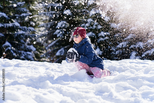 Child playing in snow on winter vacation. Snowball fight. Kid having fun in snowy forest. Family outdoors activities on Christmas holidays. Authentic lifestyle moment