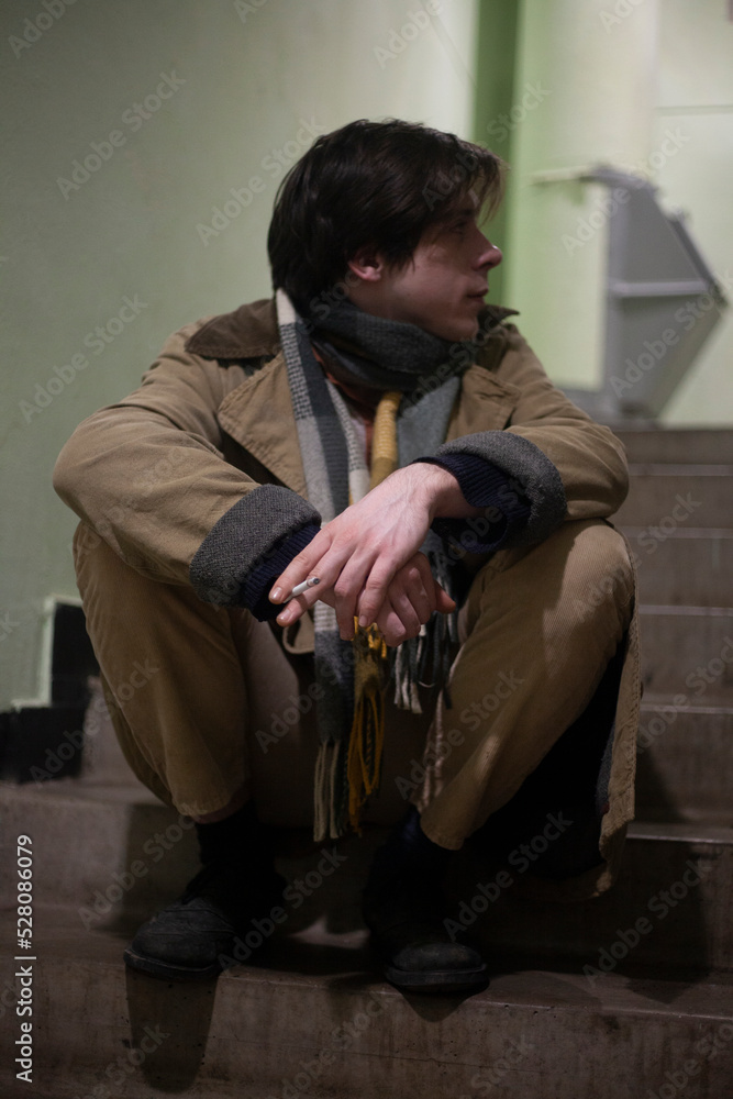 Student sits in stairwell. Young man in Russia sits on steps.