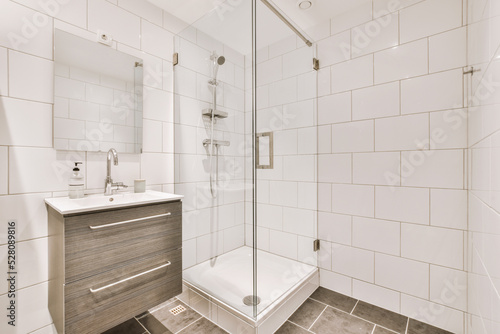 Sinks with mirrors and shower box with glass door in modern bathroom with white tiled walls