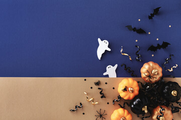 Halloween holiday card with party decorations of pumpkins, bats, ghosts on gold blue background top view. Happy halloween greeting poster in flat lay style.