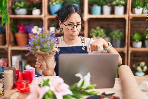 Young hispanic woman working at florist shop doing video call pointing down looking sad and upset, indicating direction with fingers, unhappy and depressed. © Krakenimages.com