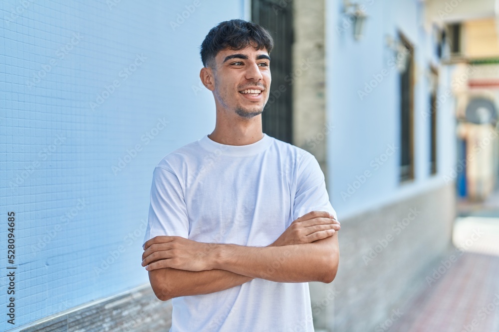 Obraz premium Young hispanic man standing with arms crossed gesture at street