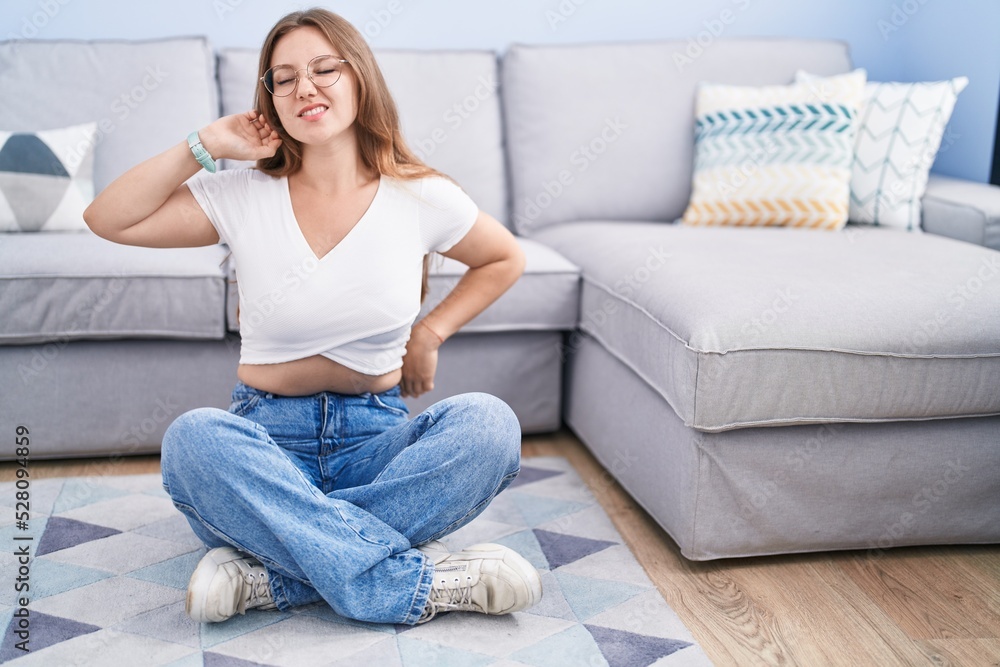Young caucasian woman sitting on the floor at the living room stretching back, tired and relaxed, sleepy and yawning for early morning