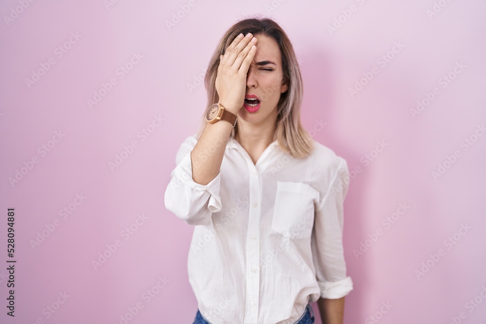 Young beautiful woman standing over pink background yawning tired covering half face, eye and mouth with hand. face hurts in pain. Young beautiful woman standing over pink background yawning tired covering half face, eye and mouth with hand. face hurts in pain.
