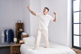 Young hispanic man smiling confident dancing on bed at bedroom